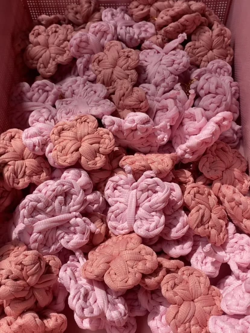 Uma pilha de flores em fio de malha rosa e terracota, prontas para a montagem