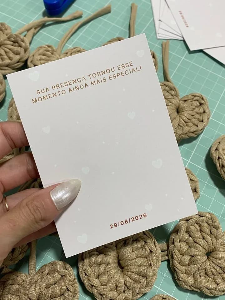 Corações de fio de malha na mesa de trabalho, ao lado do cartão da festa